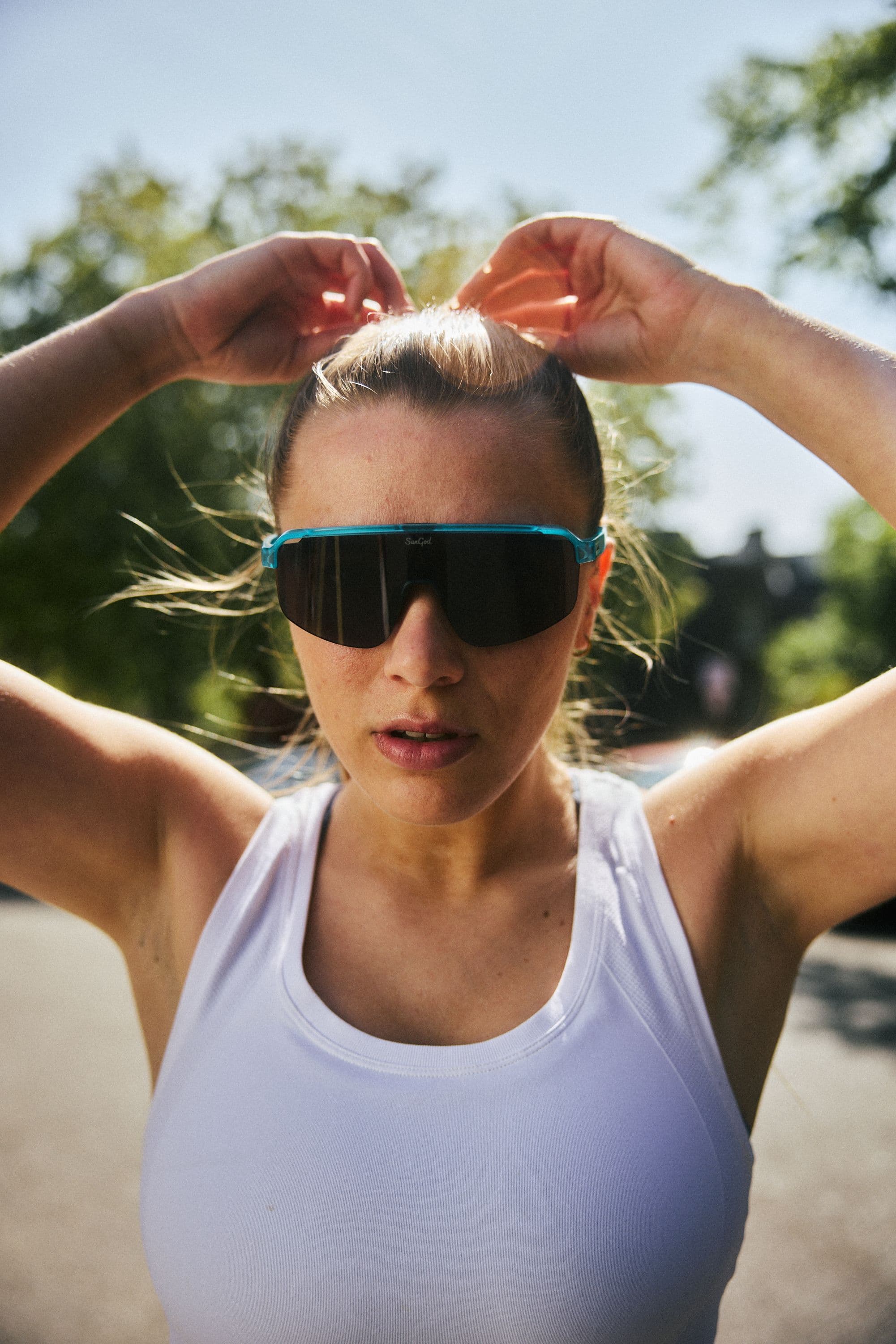 A girl in sunglasses adjusting her hair