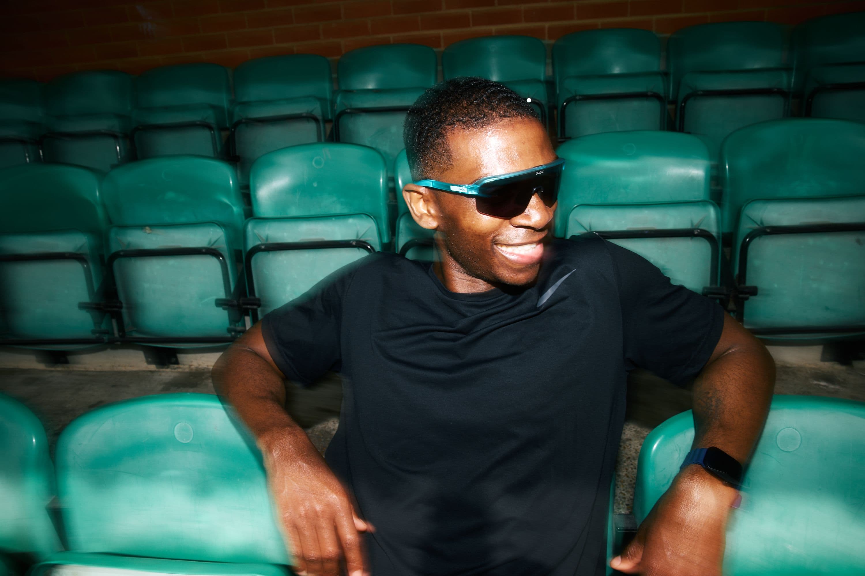 A man sat in the stands of an athletics club smiling
